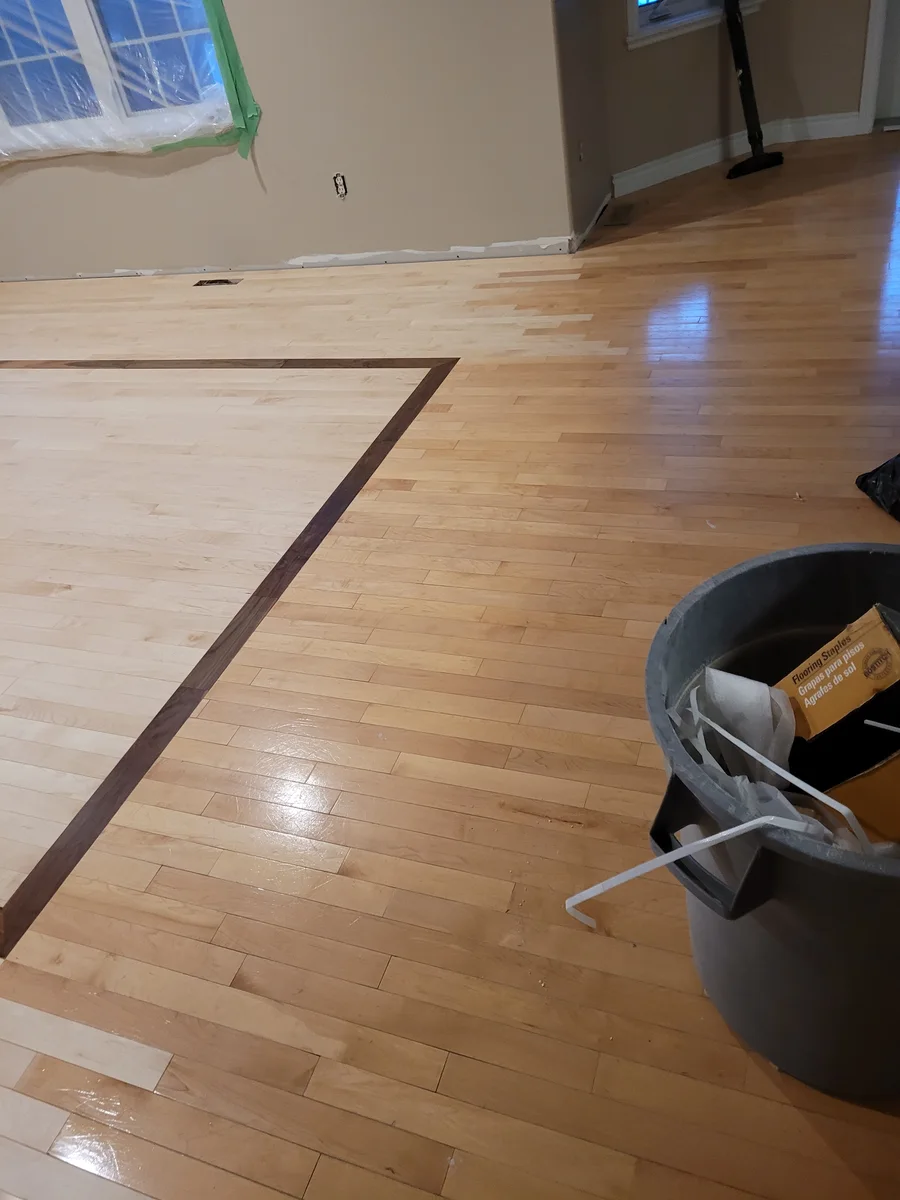 Close-up of the walnut border detail where the new hardwood transitions toward the hallway